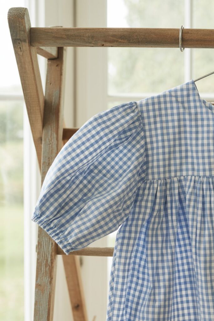 Close-up of gingham blouse air-drying on a wooden rack