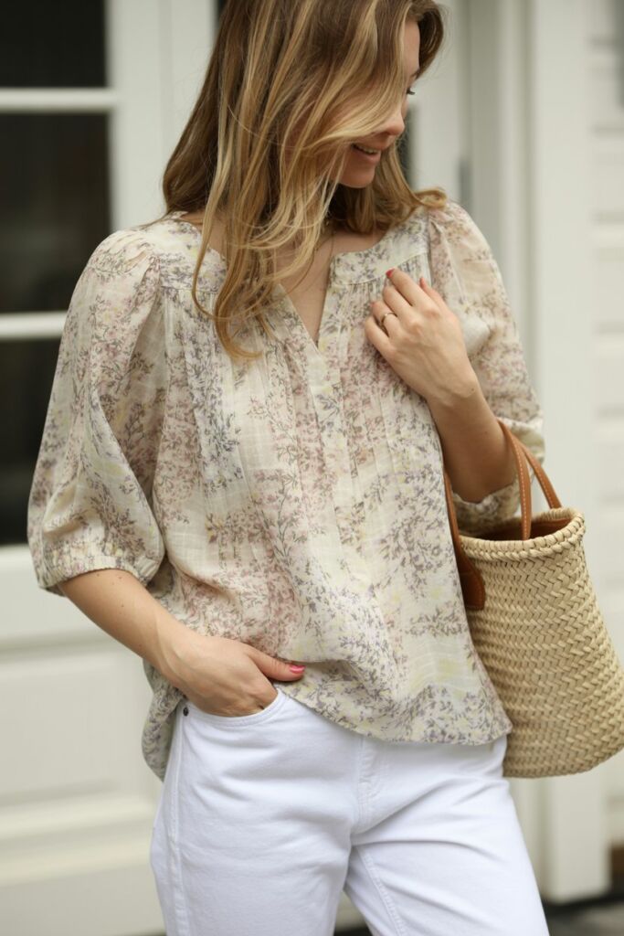 Floral print blouse paired with white denim jeans and straw bag