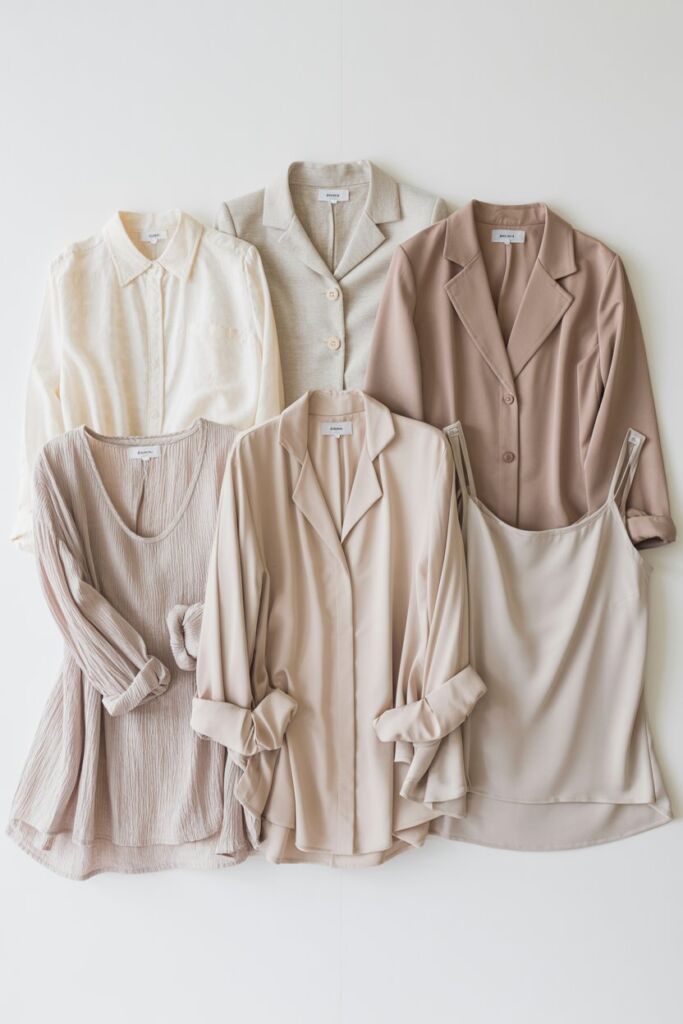Flat lay of 5 tops in neutral tones